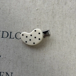 Close-up of cheese yellow polka dot duckbill hair clip with silver metal alligator clamp