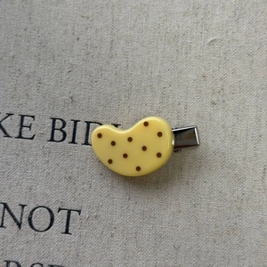 Close-up of yellow polka dot acrylic hair clip with silver metal crocodile grip