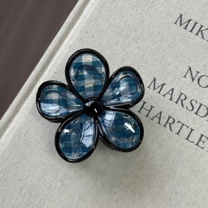 Macro di una pinza per capelli a fiore a quadretti blu e bianchi con perla nera