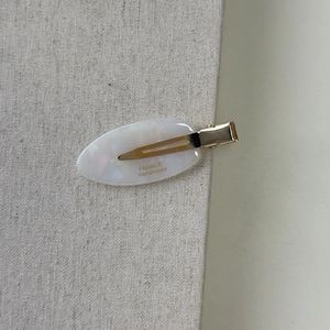 Detail shot of white marble acetate hair clip with gold metal and France Handmade logo