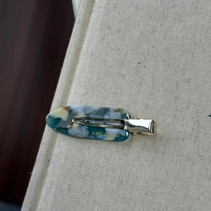 Détail d'une pince à cheveux en acétate marbré bleu et blanc avec attache dorée