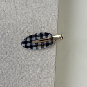 Detail of checkered acetate hair clip with gold metal clasp and handmade lettering
