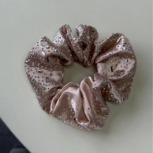 Vue détaillée du chouchou en satin rose poudré avec strass étincelants et cristaux de luxe