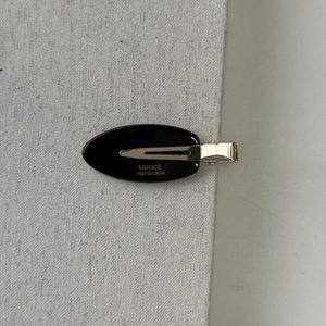 Detail of oval acetate hair clip with golden France Handmade logo and duckbill clip