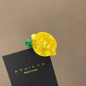 Detail of yellow acetate lemon hair claw clip with green leaves on display card