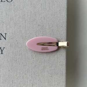 Close-up of pink oval acetate hair clip with golden France Handmade engraving details