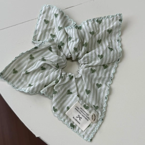 Dettaglio dell'elastico per capelli a righe verdi con cuori e bordo in pizzo