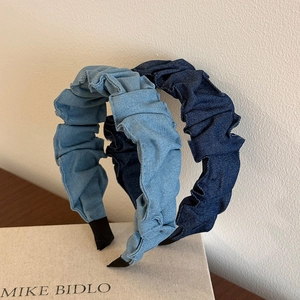 Wide pleated denim headbands in light and dark blue on a decorative book background