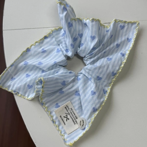 Dettaglio dello scrunchie a righe blu con cuori e bordi con cuciture gialle a onde