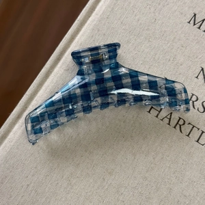 Dettaglio di una molletta per capelli a scacchi blu e bianchi su un libro materico
