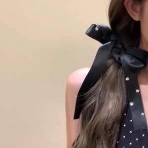Elegant black satin bow hair tie with silver star crystals worn by a model
