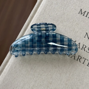 Dettaglio molletta per capelli a scacchi blu scuro con molla dorata su libro