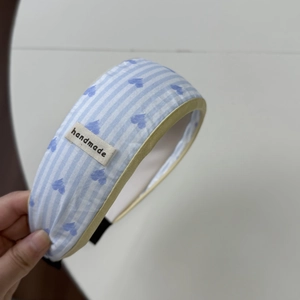 Dettaglio scrunchie a righe blu con motivi a cuore ed etichetta handmade in cotone morbido