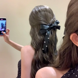 Elegant black satin bow hair tie with silver star pattern on wavy brunette hair