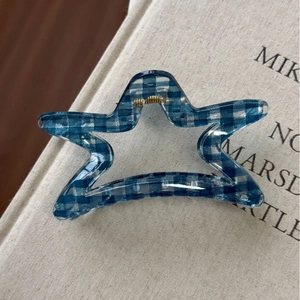 Dettaglio di pinza per capelli a stella a quadretti blu con molla dorata su libro