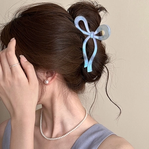 Molla per capelli a fiocco blu cangiante mostrata su un'acconciatura elegante