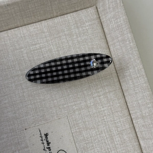 Nahaufnahme der schwarz-weißen Gingham-Haarklammer mit glitzerndem Herz-Strassstein