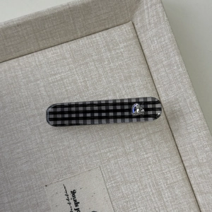 Detail der Haarklammer mit Karomuster und Herz-Strass auf beigefarbenem Tablett