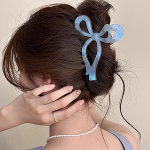 Dettaglio di un fermaglio per capelli a fiocco blu cangiante su una pettinatura