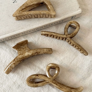 Set of four vintage amber marble hair claws in various shapes on linen background
