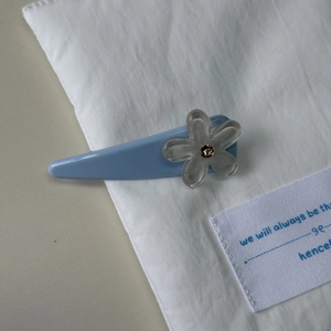 Detail of blue duckbill hair clip featuring a translucent floral motif with a crystal center