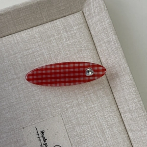 Nahaufnahme der rot-weißen Gingham-Haarspange mit herzförmigem Strass-Detail