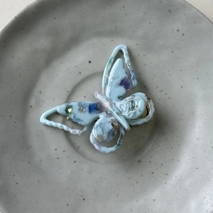 Close-up of marble acetate butterfly hair clip with SUI engraving on ceramic tray