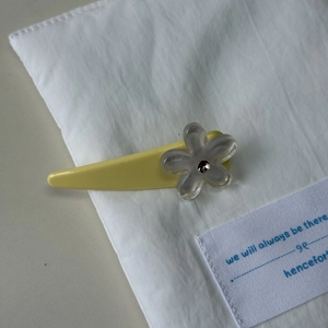 Detailed macro view of yellow flower hair clip with crystal on white cotton fabric