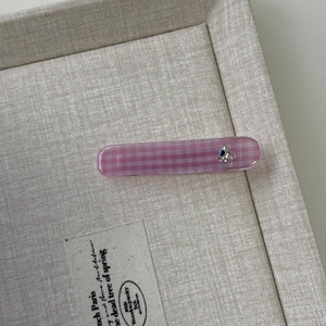 Detail der rosa karierten Acryl-Haarspange mit funkelndem herzförmigem Strassstein