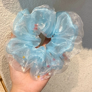Chouchou en organza bleu clair avec perles et perles colorées tenu à la main