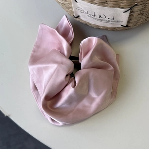 Detailed macro shot of a glossy pink satin scrunchie with smooth silk texture