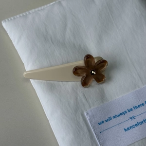 Detailed macro view of a cream hair clip featuring a translucent brown floral accent