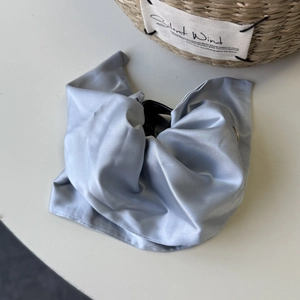 Detail of elegant silver-blue satin hair claw clip showing silky fabric texture on desk