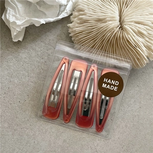 Set of four gradient red resin BB hair clips on a textured grey background with decor