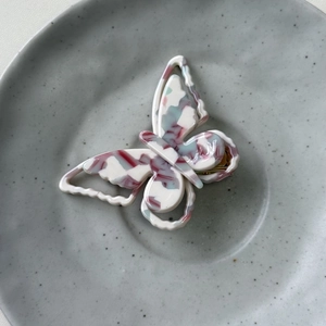 Detail of colorful butterfly hair clip with hollow wings and marbled acetate texture
