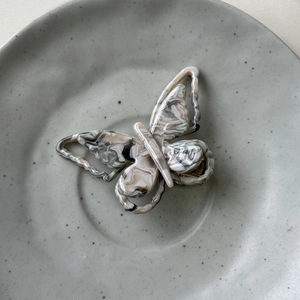 Detail view of the colorful acetate butterfly hair clip showing marble texture and metal teeth