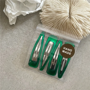 Detailed view of four dark green resin water-drop hair clips in transparent packaging