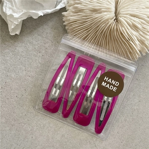 Close-up of four magenta drip paint teardrop hair clips in handmade packaging