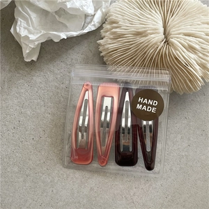 Set of four Korean drip oil water drop hair clips in a clear pouch on textured background