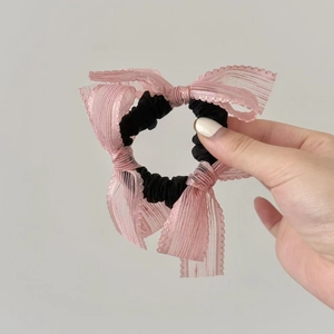 Close-up of black lace scrunchie with pink mesh bow details and delicate floral edges