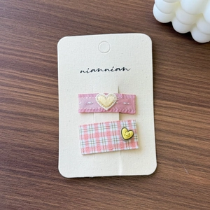 Detail of pink embroidered heart ribbon and checkered fabric hair clip set for girls