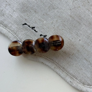 Detailed macro view of an amber acetate hair clip with vintage tortoiseshell texture
