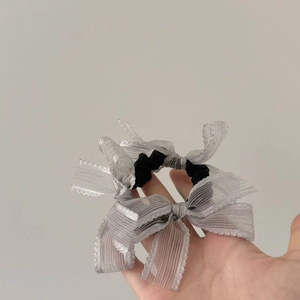 Macro detail of silver-grey organza bow hair scrunchie with striped texture