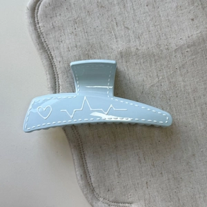 Détail d'une pince à cheveux bleue avec motif de couture et ligne cardiaque