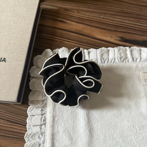 Détail d'un grand chouchou plissé noir et blanc sur un fond élégant en dentelle
