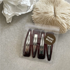Detailed view of four handmade brown resin hair clips in professional clear packaging