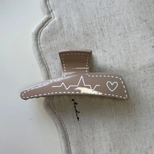 Détail de la grande pince à cheveux marron latte avec motifs de lignes de cœur