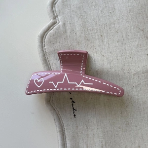 Détail de la pince à cheveux trapèze rose avec motif de cœur et ligne de pouls