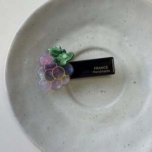 Detail view of a handmade purple grape hair clip with acrylic beads and gold trim