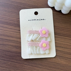 Detail of pink floral lace hair clip set on aesthetic card over wood background